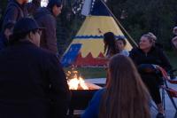 People gathered around a firepit in front of Okotoks Tipi for Fireside Stories