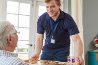 male senior and male nurse providing home care and a meal
