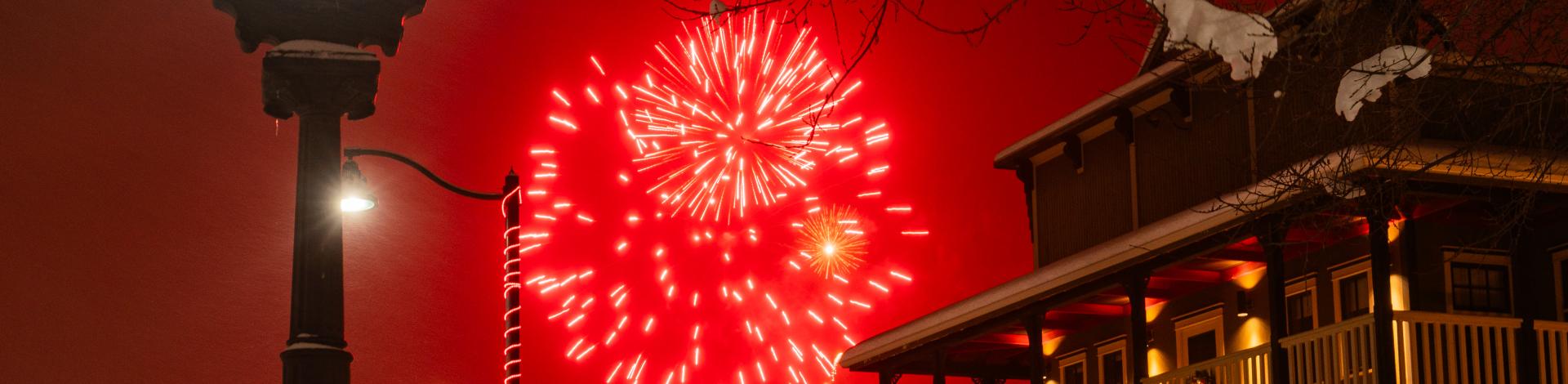Light Up Okotoks with red fireworks going off behind the plaza clock
