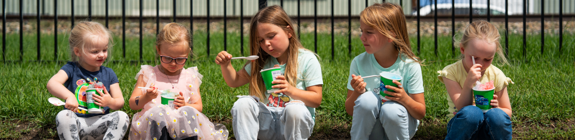 five kids sit on a curb eating