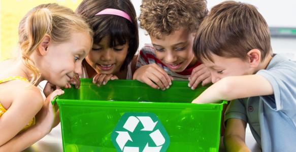 four children looking in a recycling bin