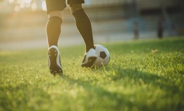 soccer player's feet dribbling ball across green soccer field