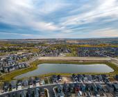 Aerial view of community homes around storm pond in Okotoks