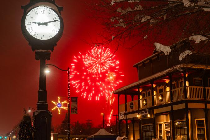 Light Up Okotoks with red fireworks going off behind the plaza clock